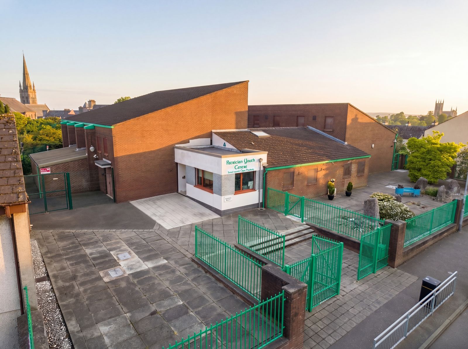 Aerial view of Patrician Youth Centre at golden hour, with the spire of St Patrick's behind